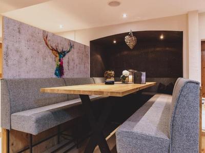 Acogedora zona de estar con tapicería gris, mesa de madera y cabeza de ciervo decorativa en la pared