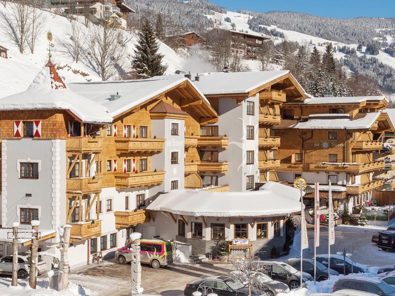 Zasněžený hotel s dřevěnou fasádou a zaparkovanými auty v zimní oblasti.