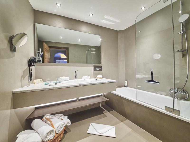 Moderní koupelna s velkou vanou, dvojumyvadly a ručníky na zemi.