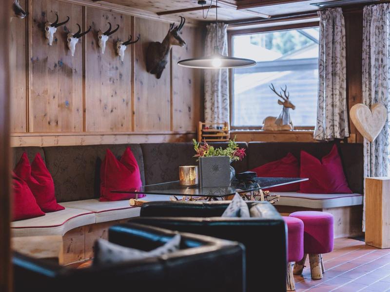 Pohodlný posezení s dřevěnými stoly, červenými polštáři a dekoracemi se zvířaty v hotelu.