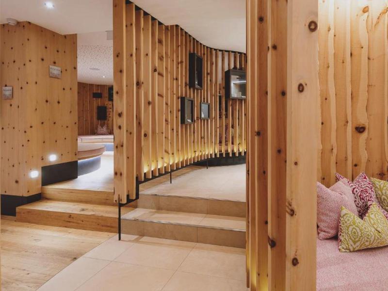 Moderní interiér hotelu s dřevěnými obklady a útulným posezením s polštáři.