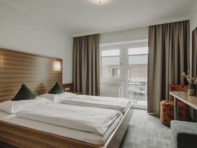 Moderne hotelkamer met tweepersoonsbed, groot raam en bureau.