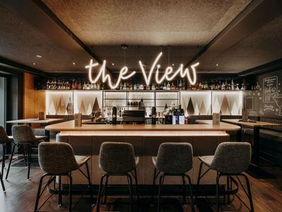 Moderne hotelbar met stijlvolle stoelen en neonbord 'the View' aan de muur