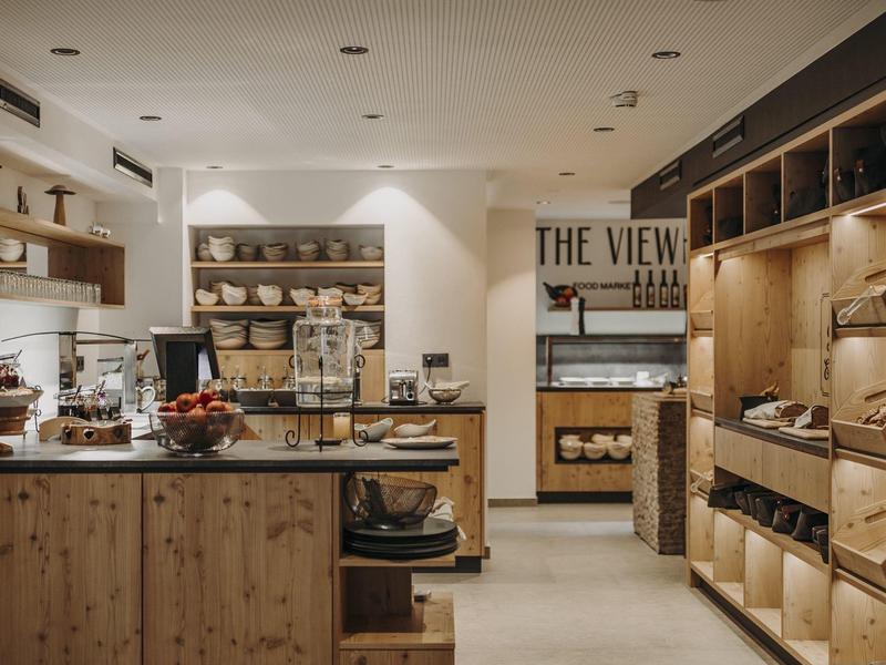 Moderne Bäckerei mit Holzregalen, Theke und Beleuchtung, helle Wände und verschiedene Backwaren.