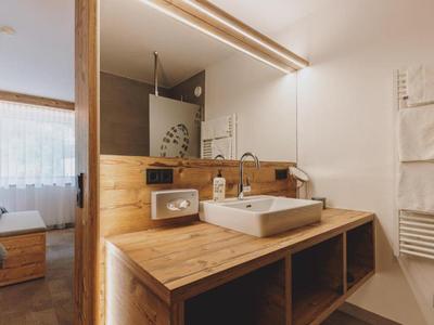 Bagno moderno con mobile in legno, lavabo rettangolare e grande specchio nella camera d'albergo.