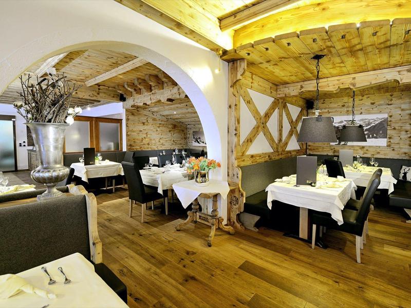 Ristorante accogliente con soffitto in legno, pareti in pietra e tavoli elegantemente apparecchiati.