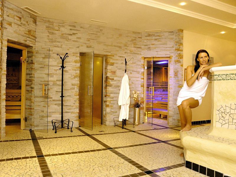 Sala relax con sauna e donna avvolta in asciugamano in una spa luminosa.