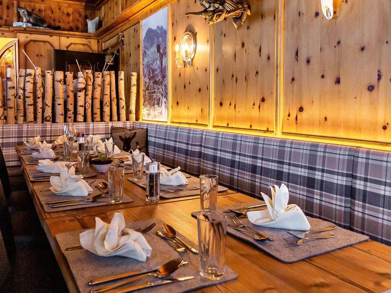 Zona ristorante accogliente e rustica con tavoli in legno, panche a quadri e tavoli apparecchiati.