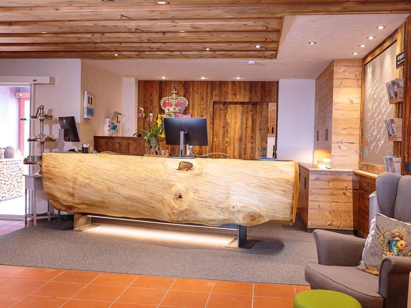 Lobby di hotel moderna con banco accoglienza rustico in legno e zone salotto accoglienti.