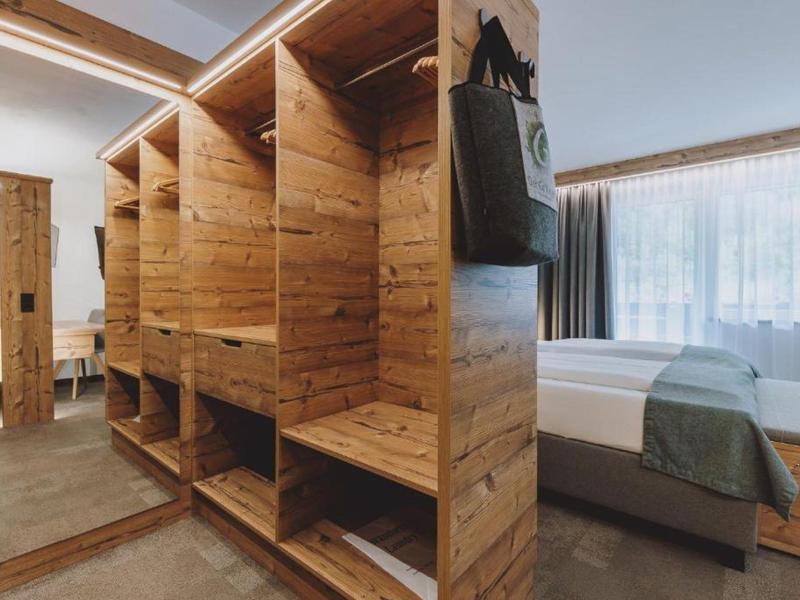 Camera d'hotel moderna con armadio in legno e letto vicino a una grande finestra.