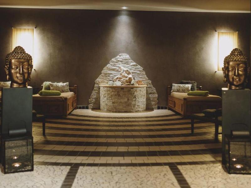 Salotto dell'hotel con camino centrale e statue decorative su piedistalli.