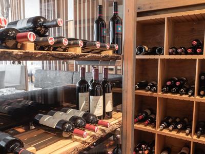 Verschiedene Weinflaschen in einem hölzernen Weinregal und auf Regalen in einem Lagerraum.