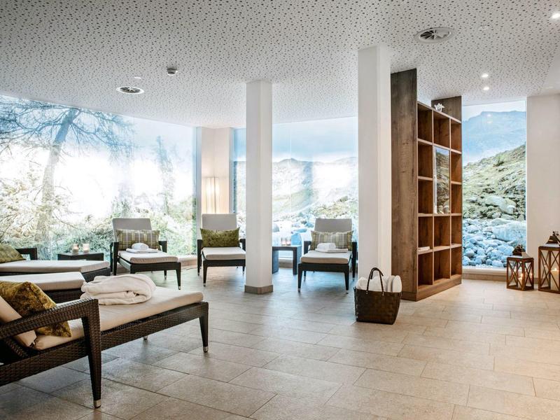 Heller, moderner Warteraum mit großen Fenstern, hellen Fliesen und einfachen Holzmöbeln.