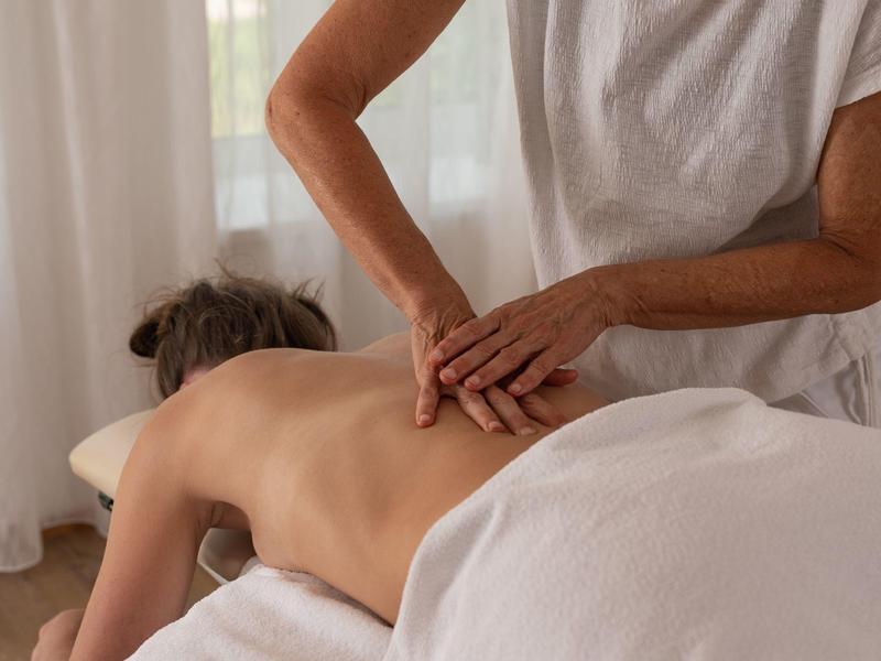 Person liegt entspannt auf Massagetisch, während Massage am Rücken durchgeführt wird.