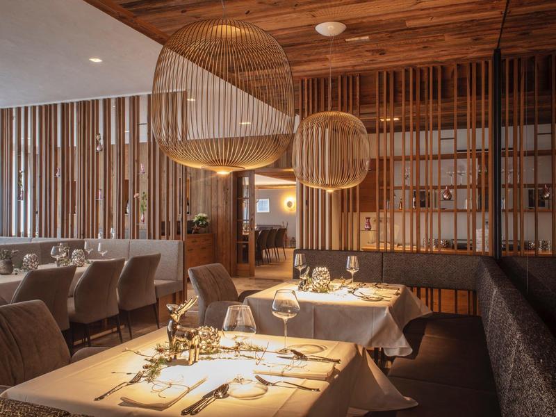 Elegantes Restaurant mit warmem Holzdekor, runden Lampen und gedeckten Tischen in gemütlicher Atmosphäre.