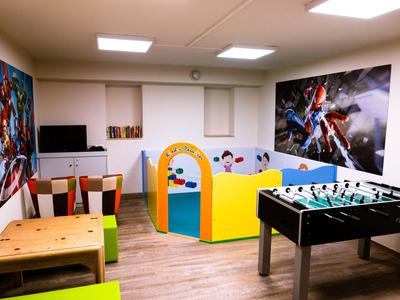 Ein bunter Spielraum mit Tischkicker, Holztisch, Spielbereich und großen Wandbildern.