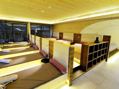 Przytulna strefa relaksu z leżankami, poduszkami i drewnianymi przegrodami w spa.