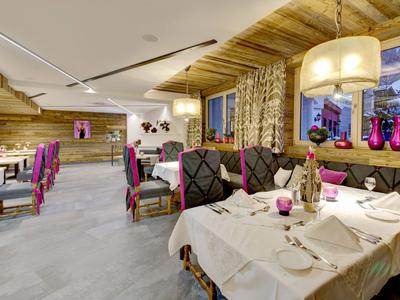 Restaurant d'hôtel cosy avec plafond en bois, nappes blanches et accents violets.