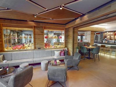 Moderne Hotellounge mit Holzverkleidung, gemütlichen Sitzecken und Barbereich.