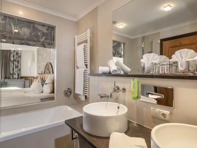 Nowoczesna łazienka z dwiema białymi umywalkami i wanną obok dużego lustra.