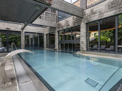 Nowoczesny basen na zewnątrz z czystą niebieską wodą i wodospadem w ogrodzie hotelowym.