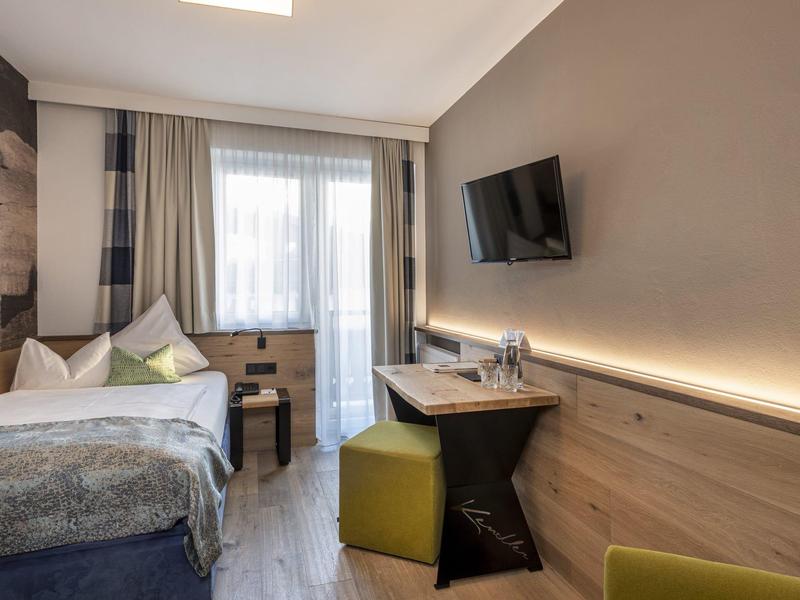 Nowoczesny pokój hotelowy z łóżkiem podwójnym, biurkiem, telewizorem i balkonem