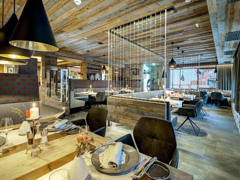 Rustykalna restauracja z drewnianym sufitem, nowoczesnymi meblami i przytulną atmosferą.