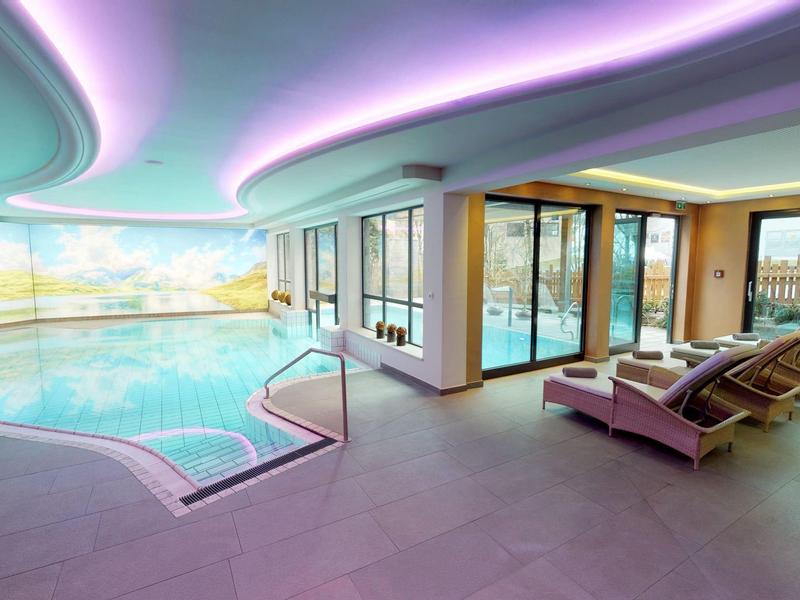 Nowoczesna strefa wellness z basenem krytym, leżakami i panoramicznymi oknami.