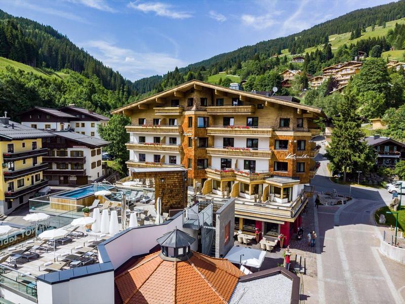 Hotel z balkonami obok basenu i gór w tle pod czystym niebem.