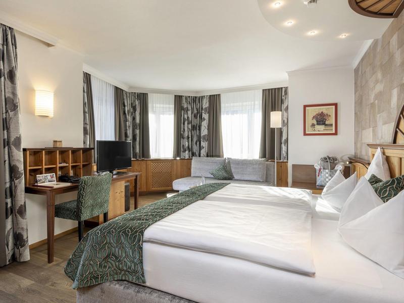 Nowoczesny pokój hotelowy z dużym łóżkiem, biurkiem i miejscem do siedzenia przy oknie