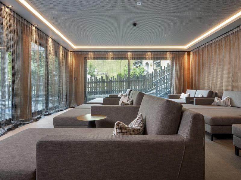 Nowoczesny salon z dużymi oknami, szarymi sofami i pośrednim oświetleniem w hotelu