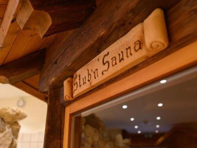 Panneau en bois portant l'inscription 'Almh Sauna' au-dessus d'une cabine de sauna encadrée de bois