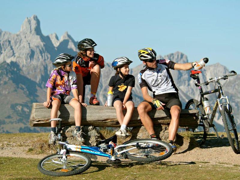 Famille fait une pause vélo sur un banc avec paysage montagneux