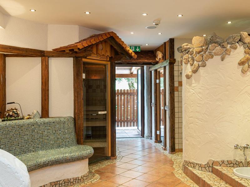 Espace spa confortable avec sauna, banc et accès à la terrasse extérieure.