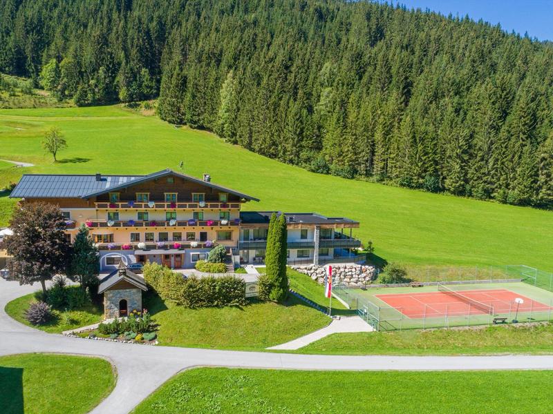 Hôtel avec court de tennis entouré de prairies vertes et de forêts