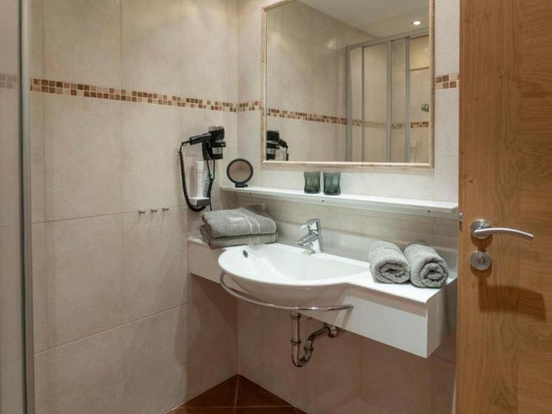 Salle de bain d'hôtel compacte avec lavabo moderne, grands miroirs et serviettes.