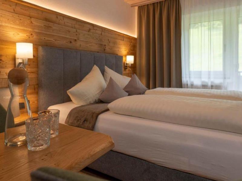 Chambre d'hôtel confortable avec lit double, mur en bois et lampe de chevet.