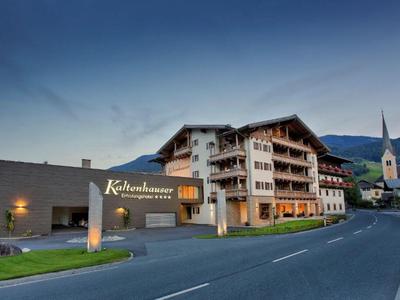 Edificio di hotel moderno in stile alpino tradizionale al crepuscolo su una strada di montagna.