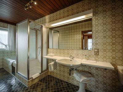 Łazienka z prysznicem, umywalką i toaletą, rustykalna z wzorzystymi płytkami i drewnianym sufitem.