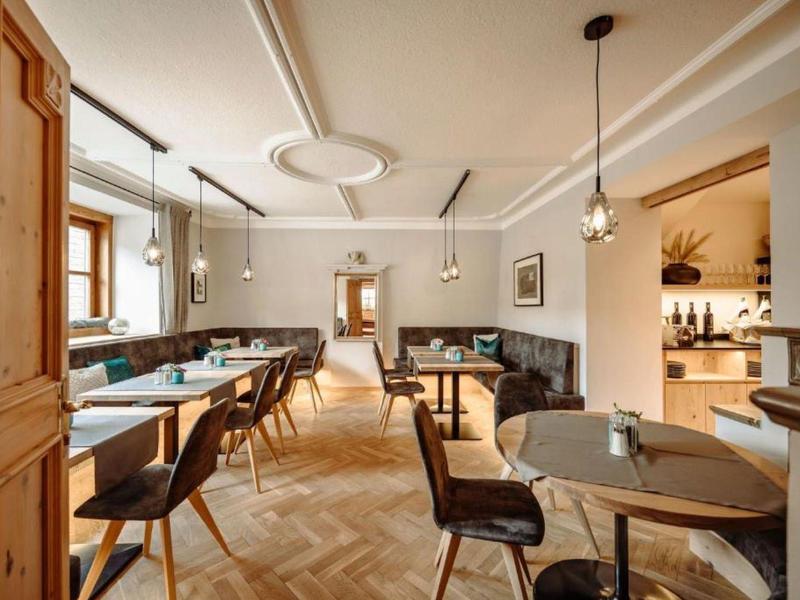 Nowocześnie urządzona jadalnia z stołami, krzesłami i wygodną ławką w jasnym pomieszczeniu.