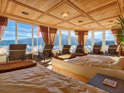 Przytulna część pokoju hotelowego z łóżkami i panoramicznymi oknami z widokiem na góry.