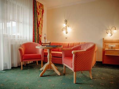 Przytulny kącik z czerwonymi tapicerowanymi meblami i drewnianym stolikiem w pokoju hotelowym.