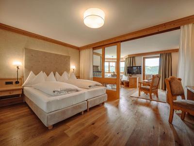 Nowoczesny pokój hotelowy z łóżkiem podwójnym, częścią wypoczynkową i dużym oknem z widokiem na zewnątrz.