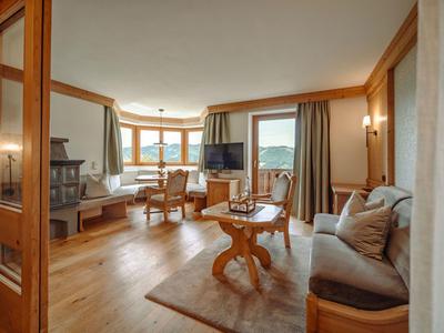 Jasny salon z drewnianymi panelem, wygodnymi miejscami do siedzenia i widokiem na góry.