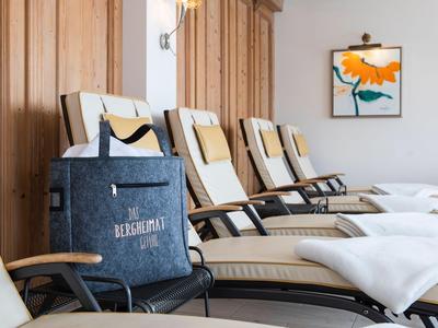 Ligstoelen met comfortabele kussens naast houten muren in een lichte wellnessruimte.