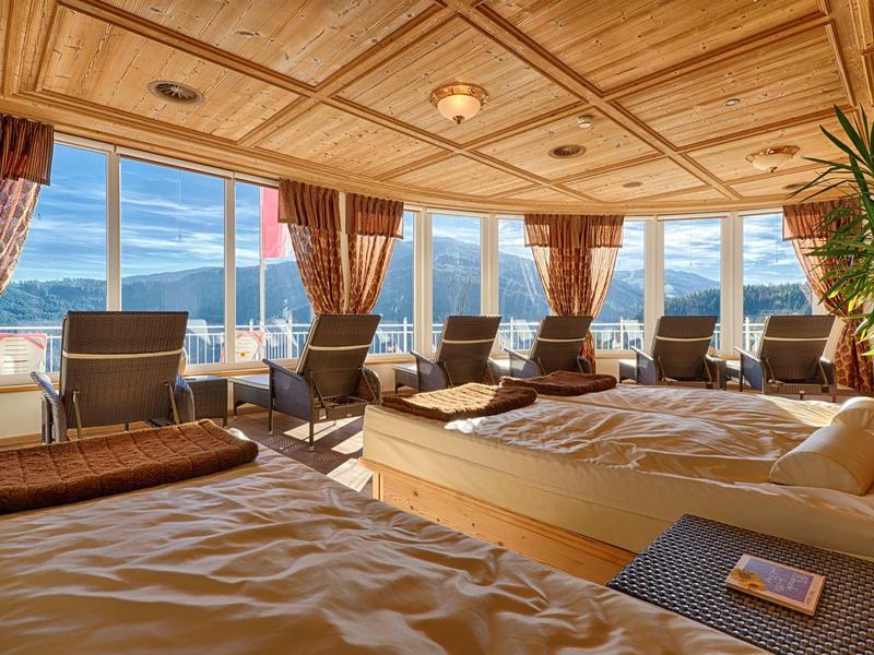 Przytulna część pokoju hotelowego z łóżkami i panoramicznymi oknami z widokiem na góry.