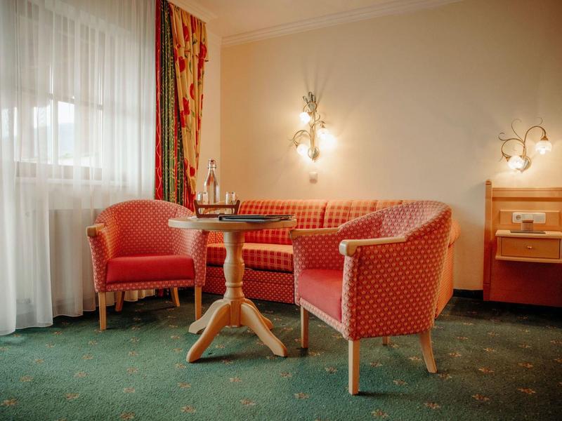 Przytulny kącik z czerwonymi tapicerowanymi meblami i drewnianym stolikiem w pokoju hotelowym.