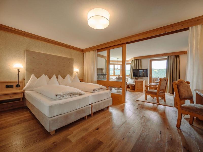 Nowoczesny pokój hotelowy z łóżkiem podwójnym, częścią wypoczynkową i dużym oknem z widokiem na zewnątrz.