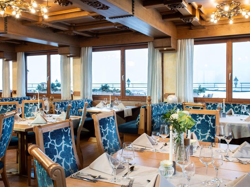 Elegancka restauracja z niebieskimi krzesłami i panoramicznym widokiem na wodę.