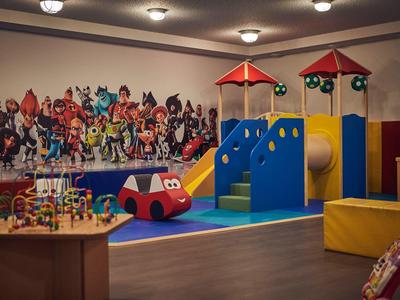 Colorful indoor playground with slide, climbing structure, and wall decoration in a hotel.